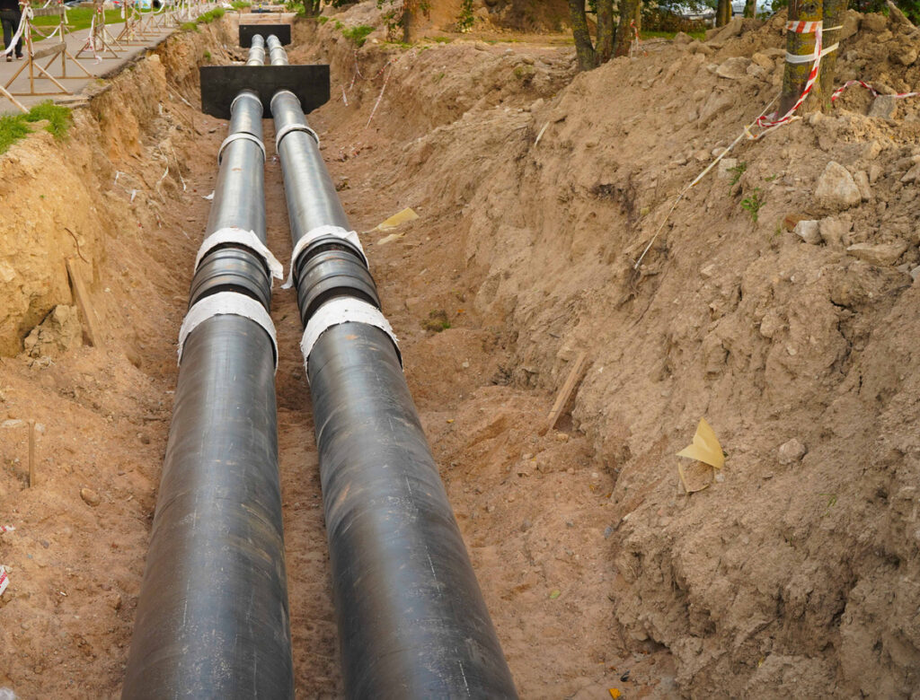 Replacement main sewer line for a residential neighborhood, pipes exposed within a dirt