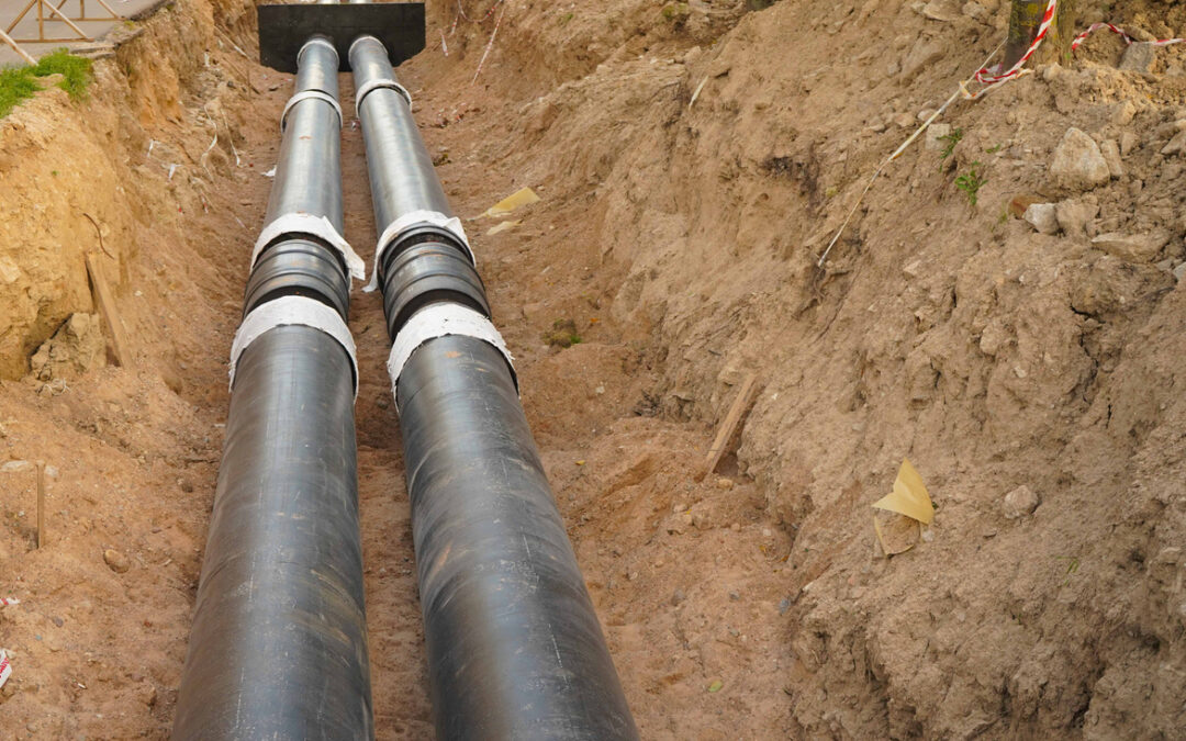 Replacement main sewer line for a residential neighborhood, pipes exposed within a dirt
